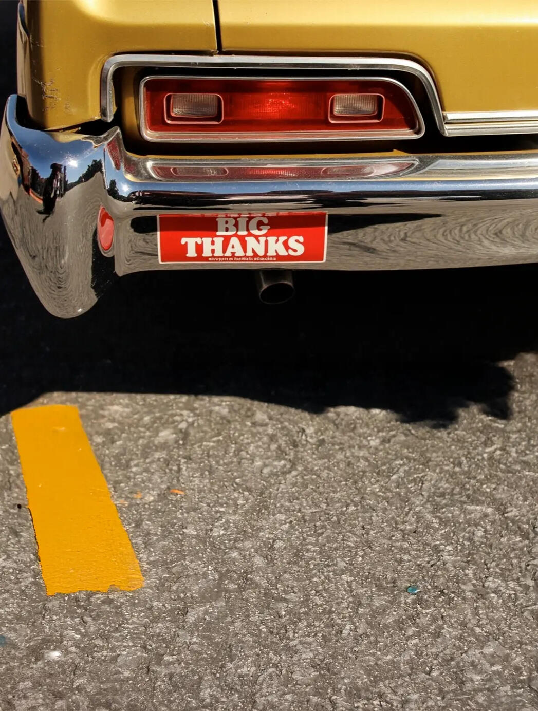 Big Thanks Marketing - Driving Business Growth Close-up of a vintage gold car's bumper with a red 'Big Thanks' bumper sticker, reflecting a city street. Symbolizing marketing that drives business forward.